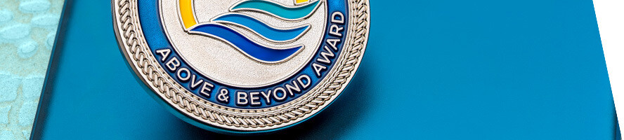 Above and Beyond Award coin with silver rope edge and layered blue wave artwork