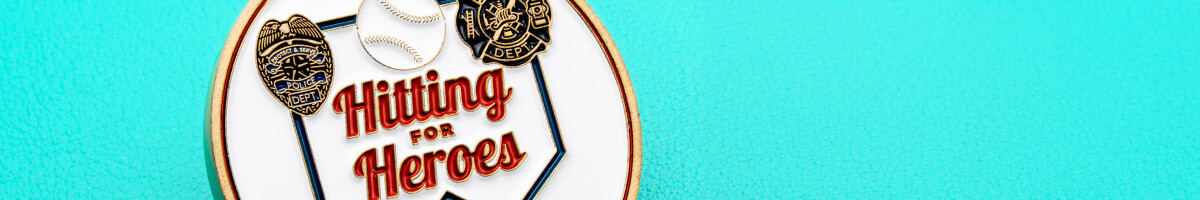 Close-up of a baseball charity coin reading "Hitting for Heroes" with police and fire badges