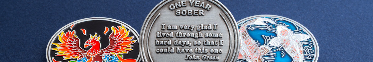 Phoenix, one-year-sober, and koi AA sobriety coins side by side