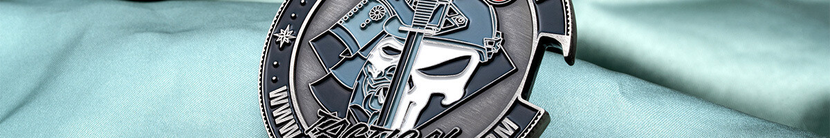 Close crop of the Bushido Tactical bottle opener coin showing the masked warrior skull behind a sword