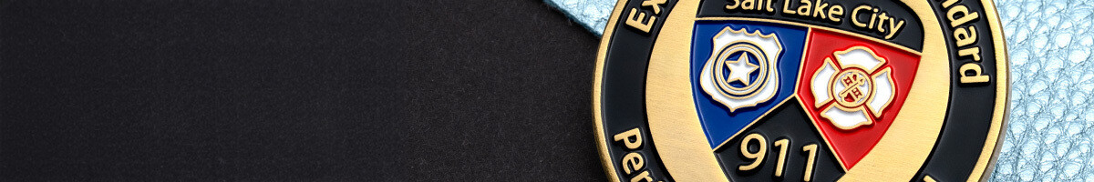 Close-up of a Salt Lake City 911 challenge coin showing a police, fire, and 911 shield in blue, red, and black enamel