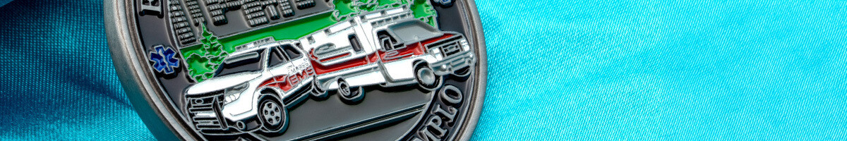 EMS challenge coin detail showing a sculpted ambulance and supervisor SUV against a city skyline
