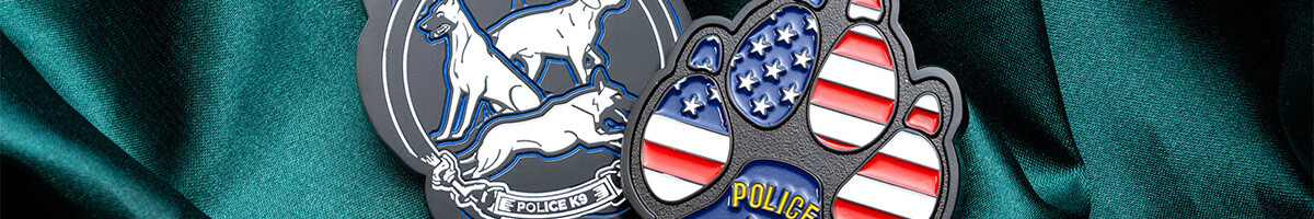Two paw-shaped police K9 challenge coins side by side, one engraved with the unit's dogs and one filled with American flag enamel