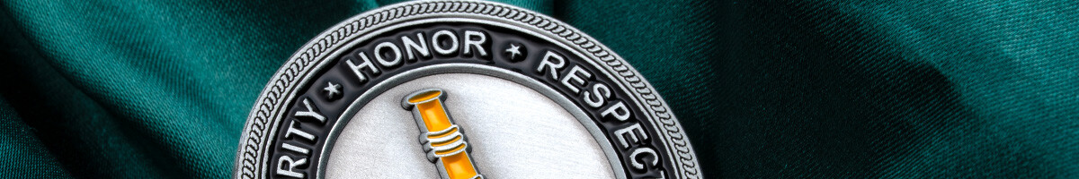 Close-up of an antique silver Herrmann fire company coin with Integrity, Honor, and Respect around the rim and a brass nozzle in the center