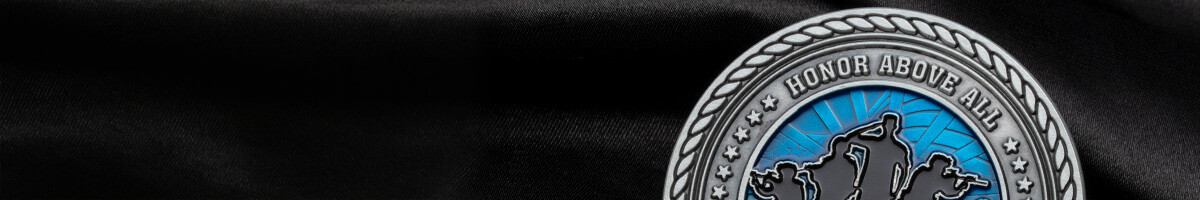 Close-up of the Steelcase Salutes antique silver coin reading Honor Above All with soldier silhouettes on a blue enamel field