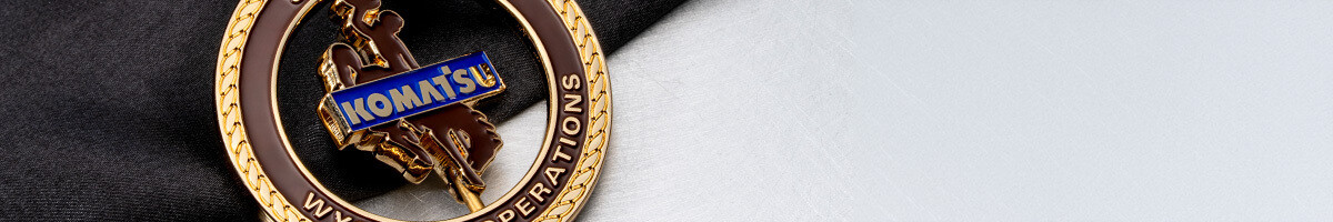 Close crop of the Komatsu Wyoming Operations spinner coin showing the bucking horse and blue Komatsu bar