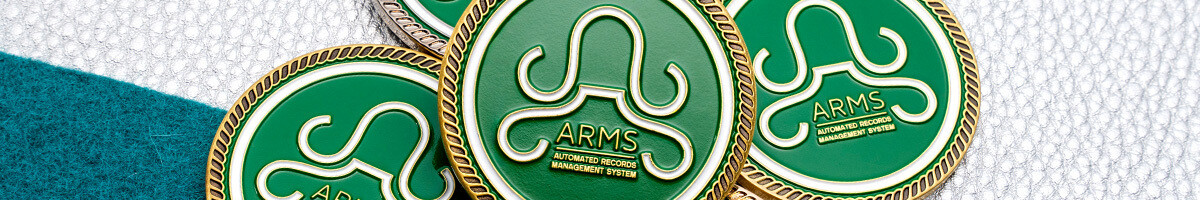 Close-up of stacked green ARMS Automated Records Management System coins with gold rope rims