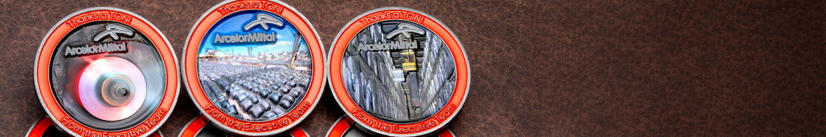 Three ArcelorMittal coins side by side, each set with a different mill and warehouse scene inside an orange enamel rim