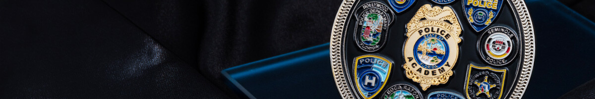 Silver and black police academy coin ringed with enamel agency badges around a gold central academy badge