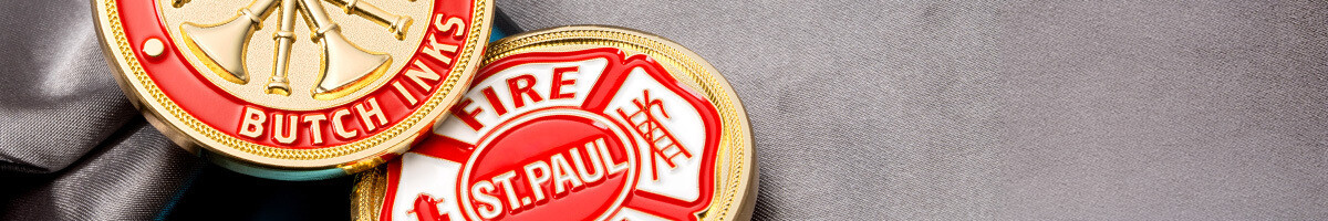 Close-up of red and gold St. Paul Fire Dept and Fire Chief Butch Inks challenge coins