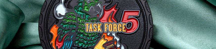 Close-up of a black Task Force 5 firefighter challenge coin with a helmeted parrot and flames