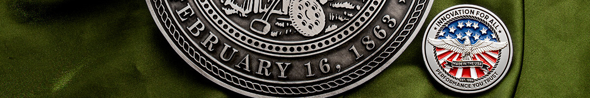 Close-up of an antique silver Kansas State University display coin rim beside a standard size enamel challenge coin
