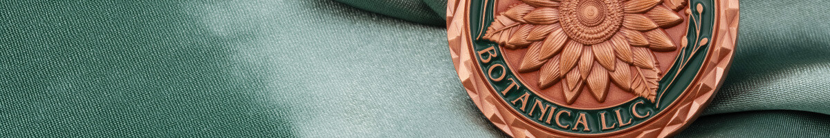 Close-up of a copper and green Botanica LLC coin with a sculpted sunflower and diamond-cut rim