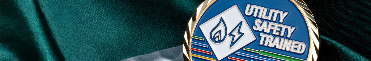 Close-up of a utility safety trained challenge coin with a gas flame and lightning bolt emblem in blue enamel